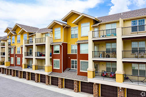 Apartment building with balconies and cars parked on the street.