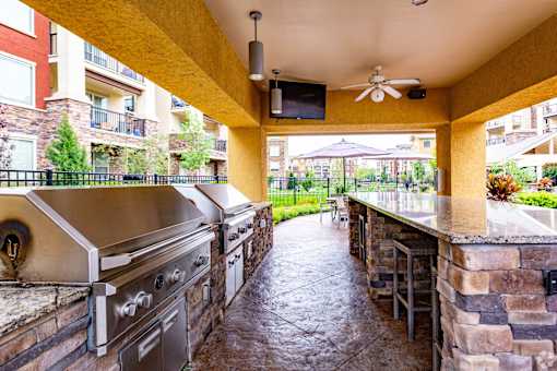 A patio with a stone wall and a grill.