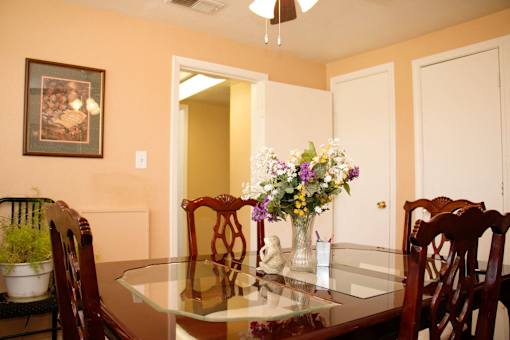 A dining room with a table and chairs at North Village Apartments in Kansas City, MO.