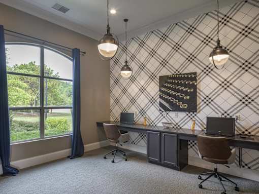 A room with a desk, chairs, and a window with curtains.