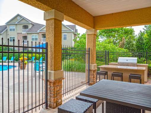 A patio with a table and chairs overlooking a pool.
