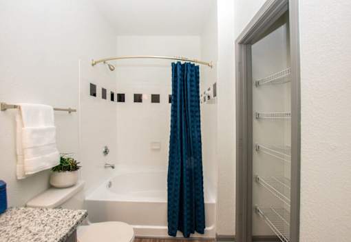 A small bathroom with a white tub and a blue shower curtain.