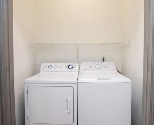 Two white front loading washing machines in a small laundry room.