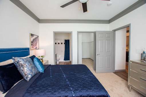 A bedroom with a bed, dresser, and ceiling fan.