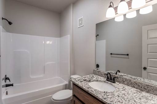 A bathroom with a white tub, sink, and toilet.