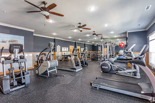 A gym with treadmills, elliptical machines, and other exercise equipment.
