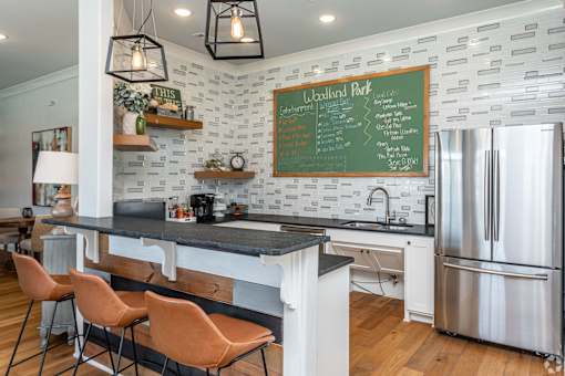 A kitchen with a black counter top and a chalkboard menu on the wall.