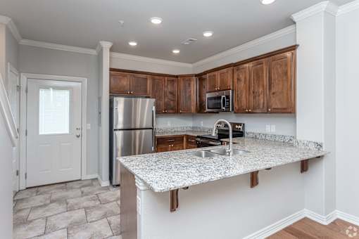 A kitchen with a granite countertop and wooden cabinets.