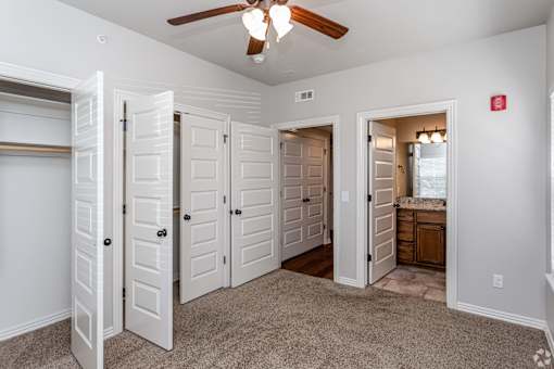 A room with a ceiling fan and white doors.