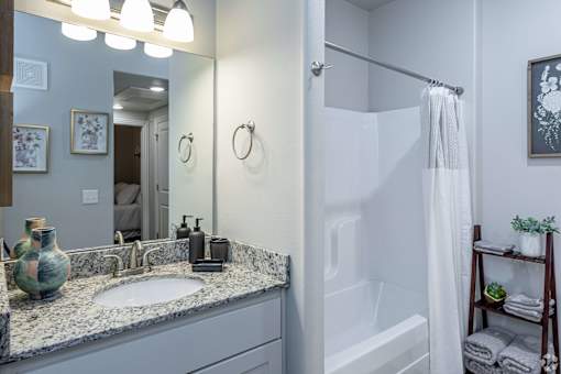 A bathroom with a sink, mirror, and shower.