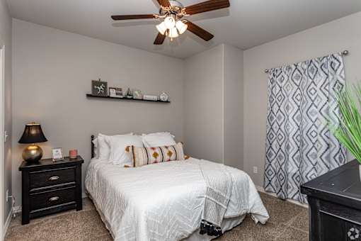 A bedroom with a white bed and a ceiling fan.