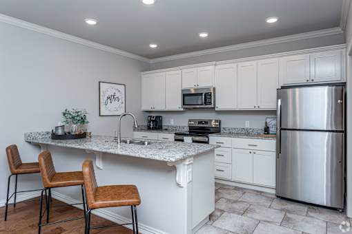 A kitchen with white cabinets and a stainless steel refrigerator.
