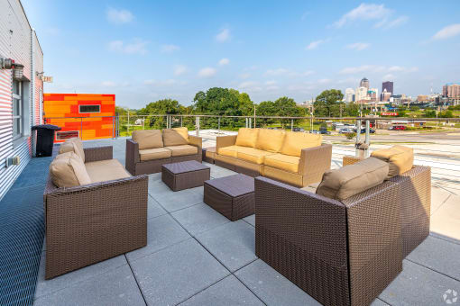a rooftop patio with furniture and a city in the background