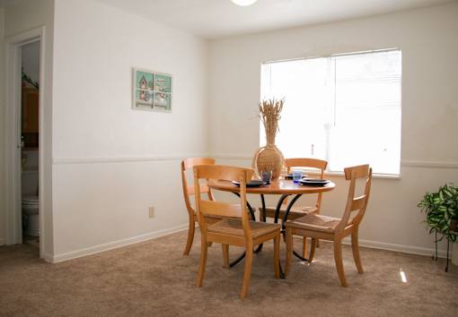 A dining room with a table and chairs at North Village Apartments in Kansas City, MO.