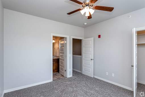 A room with a ceiling fan and two doors, one of which is open.