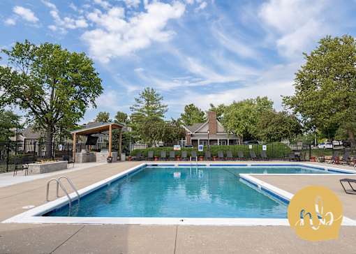 A large outdoor swimming pool surrounded by trees and a covered area.