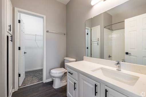 A white bathroom with a toilet, sink, and mirror.