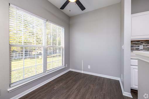 A room with a window covered by white blinds and a ceiling fan.