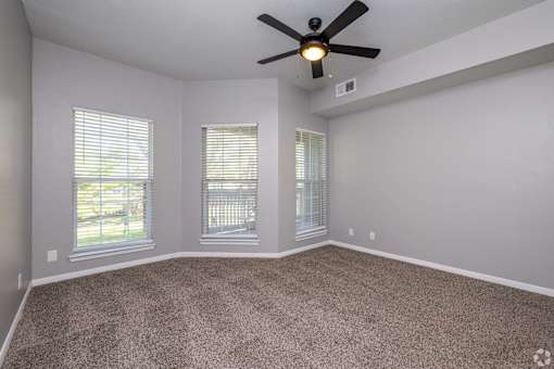 A room with a ceiling fan and carpeted floor.