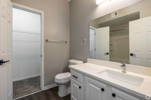 A white bathroom with a toilet, sink, and mirror.