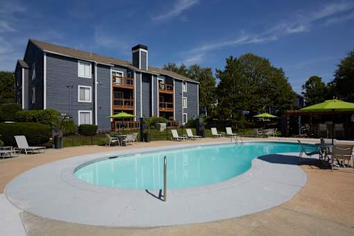 A swimming pool in front of a grey apartment building.