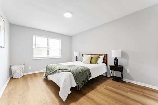 A bedroom with a bed, nightstand, and window.
