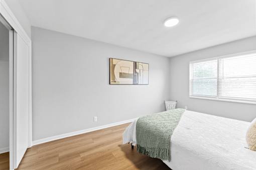 A bedroom with a bed, a nightstand, and a painting on the wall.