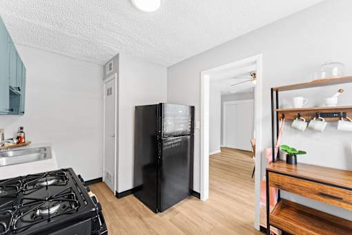 A black refrigerator sits in a kitchen next to a stove.