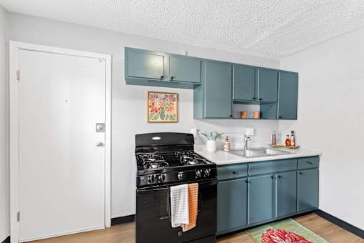 A kitchen with a black stove top oven and teal cabinets.