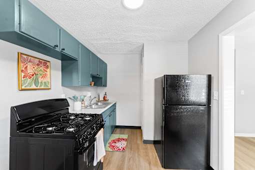 A black stove in a kitchen with a white wall and a framed picture hanging above it.