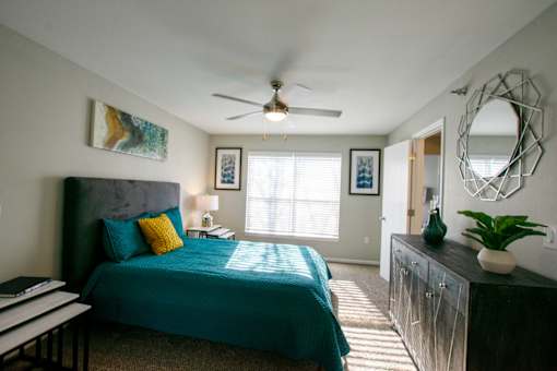 A bedroom with a bed, a dresser, and a mirror.