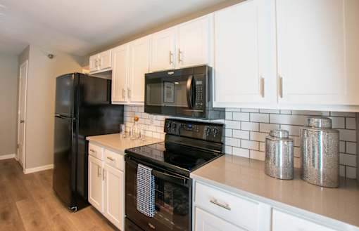 A kitchen with black appliances and white cabinets.