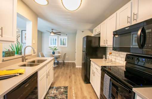 A modern kitchen with black appliances and white cabinets.