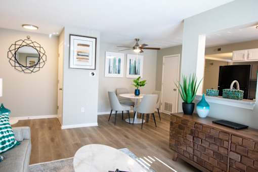 A living room with a grey couch, a white coffee table, a wooden cabinet, and a mirror on the wall.