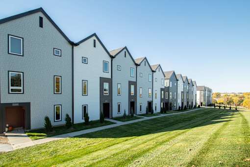 A row of houses with a green lawn in front.
