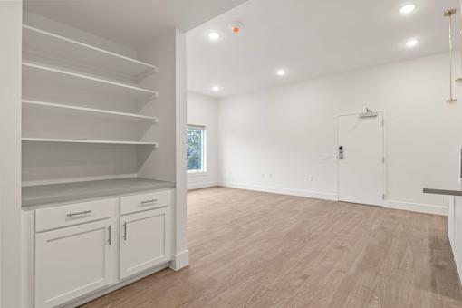 A white room with wooden floors and a staircase on the left side.