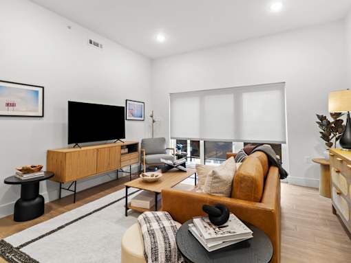 A living room with a brown sofa, a black table, and a TV.