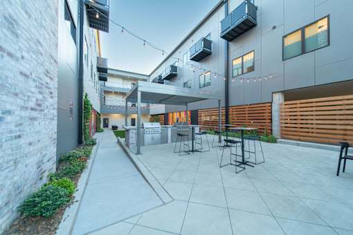 A patio area with a table and chairs is surrounded by a brick wall and a wooden fence.