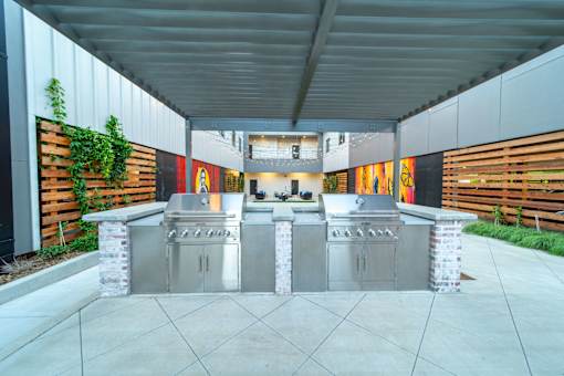 A modern outdoor kitchen with two grills and a counter.