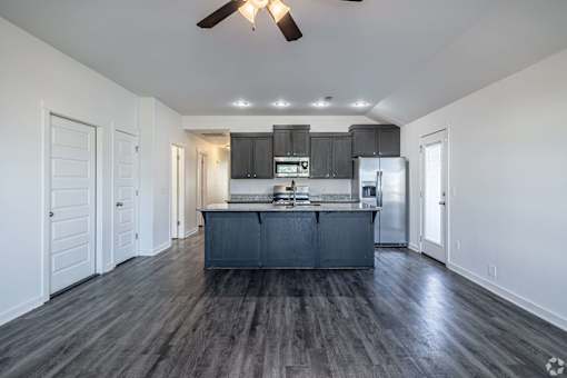 A kitchen with a dark wood floor and white walls.