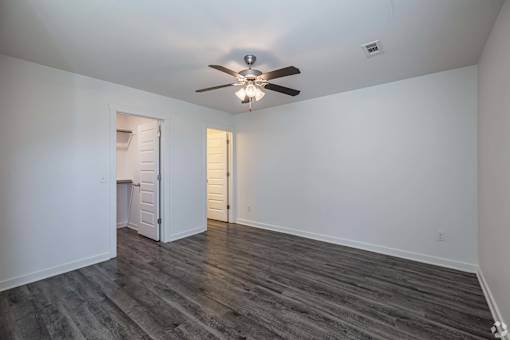 A room with a ceiling fan and wooden flooring.