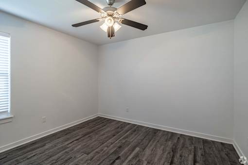 A room with a ceiling fan and wooden flooring.