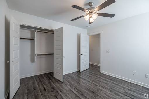 A room with a ceiling fan and a closet with a sliding door.