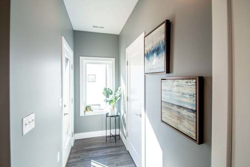 A hallway with a table and two framed pictures on the wall.