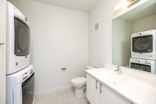 a washer and dryer in a bathroom with a toilet and a sink