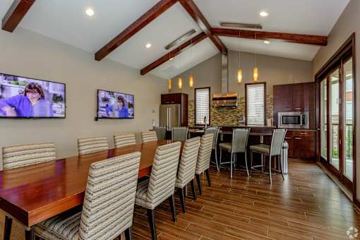 A modern dining room with a long wooden table and chairs.