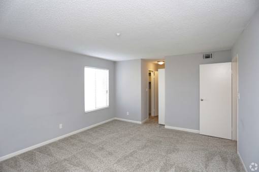 A room with a carpeted floor and a window.