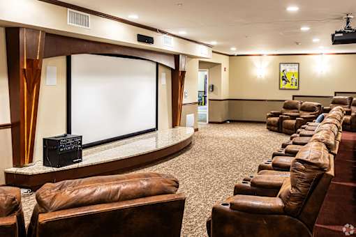 A row of brown leather chairs are arranged in front of a large screen.