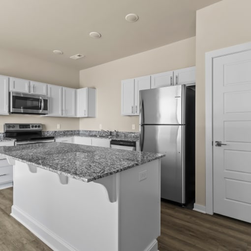a kitchen with granite counter tops and a stainless steel refrigerator at Hillcrest Village, Springdale