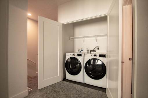 A laundry room with two washing machines and a white door.